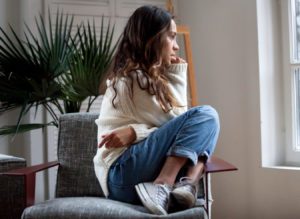 Sad thoughtful girl sitting on chair feeling depressed or lonely