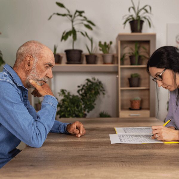 A senior man watches as a therapist completes an assessment and explains the cost of dual diagnosis treatment without insurance