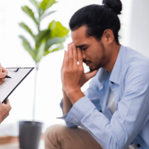 A man closes his eyes and puts his hands partially over his face during an assessment for Optum drug and alcohol rehab