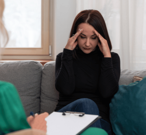 A woman with her head down as a therapist explains counseling and therapy for substance abuse