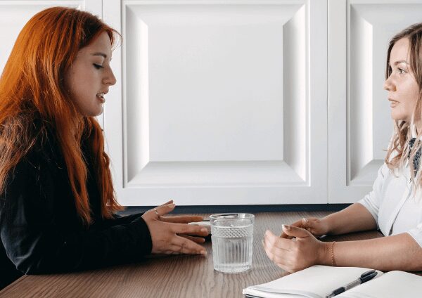 Young woman talking to her therapist at a private luxury rehab facility