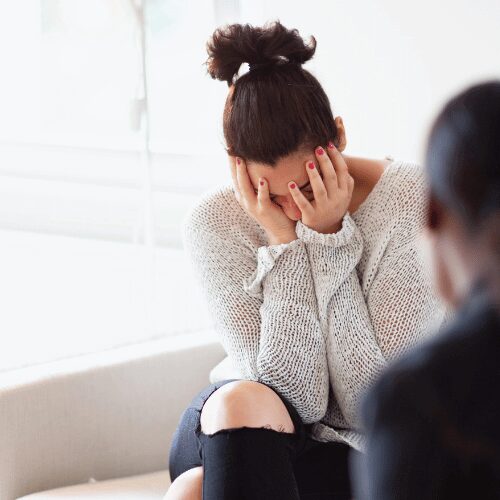 A young woman hiding her face in her hands while meeting with a therapist at a residential meth addiction treatment center