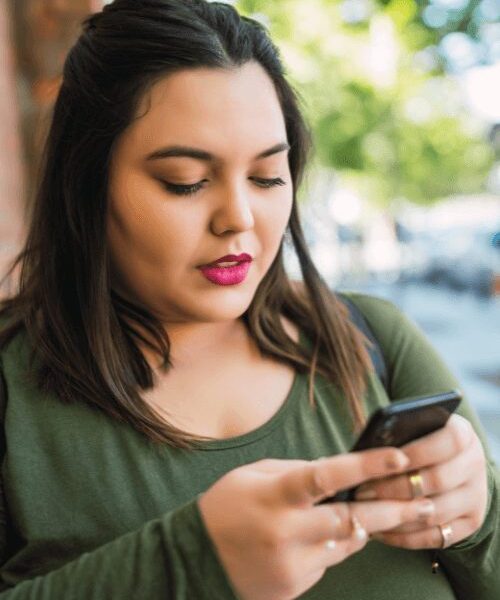 Woman outdoors checking her phone for BCBS addiction rehab coverage