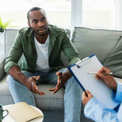 Man talking to a substance addiction therapist at a behavioral health center for drug and alcohol rehab