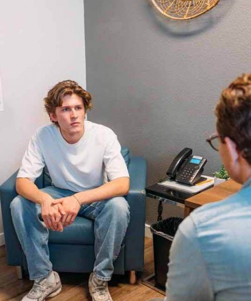 A man listens as a therapist explains addiction treatment programs that insurance covers